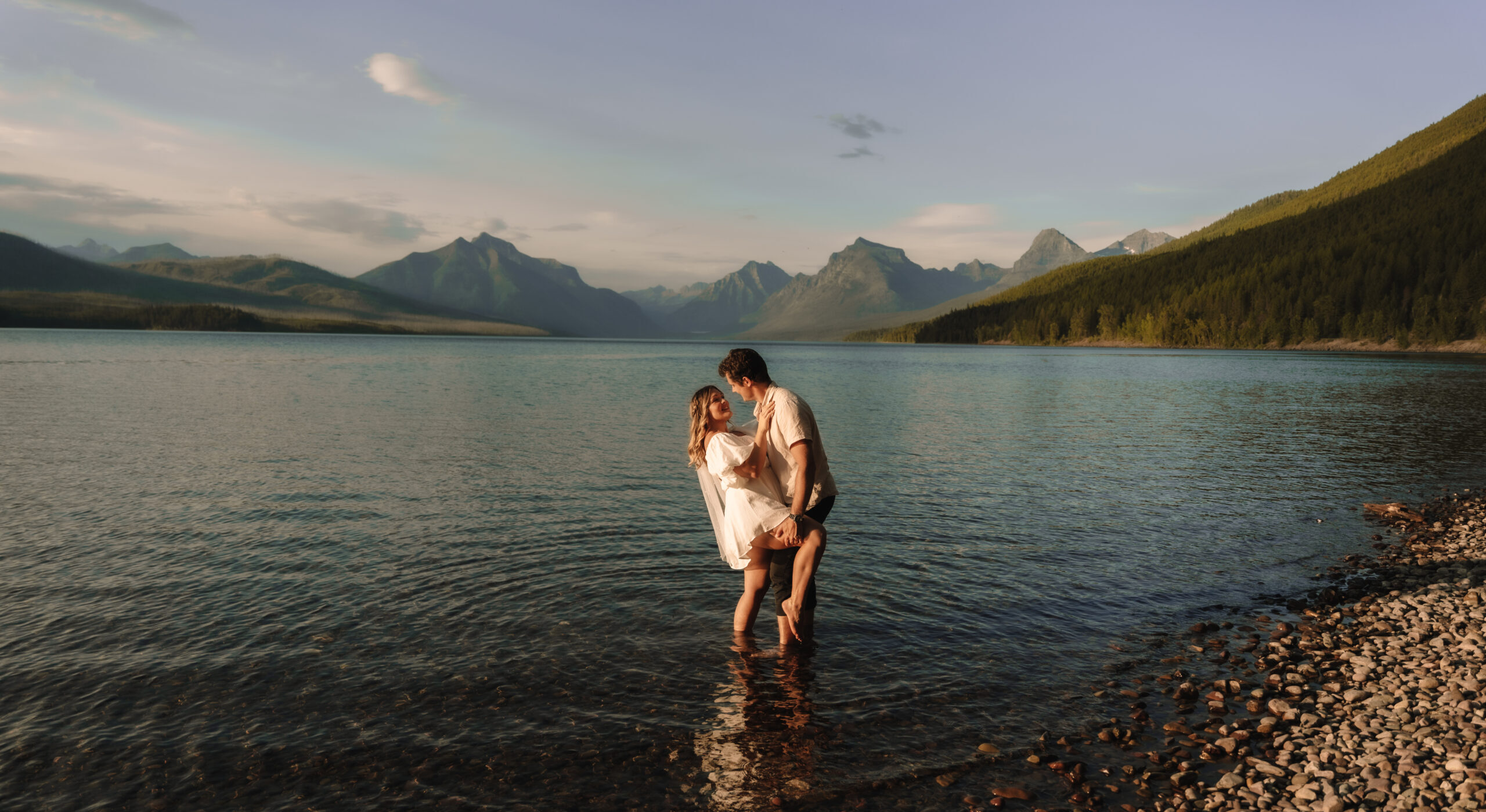 Glacier National Park elopement couple standing in the water at Lake MacDonald with the Mountains in the background