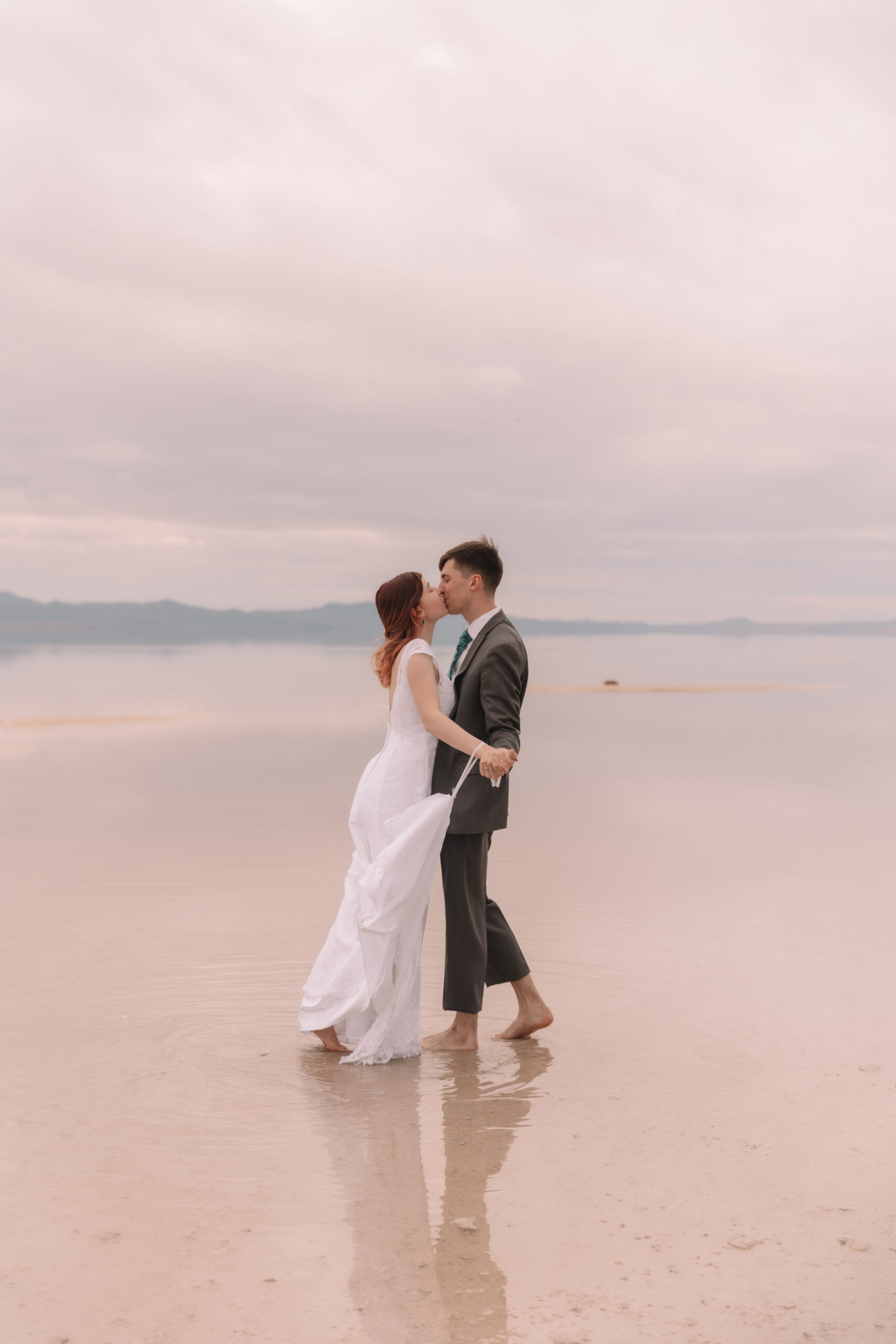 Elopement couple slow dancing and kissing on the flooded salt flats in Utah