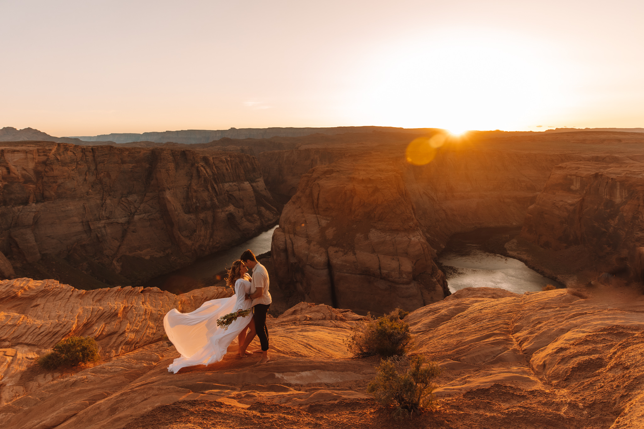 Horseshoe Bend elopement couple in Page, Arizona standing in front of the red and orange canyons as the sun is setting
