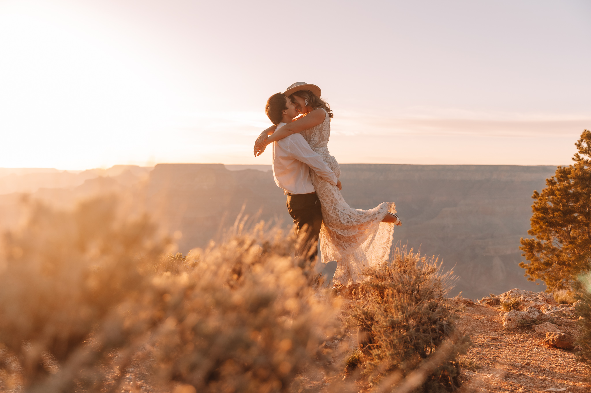 Elopement couple standing on the edge of a cliff at The Grand Canyon in Arizona with the vast canyons in the background