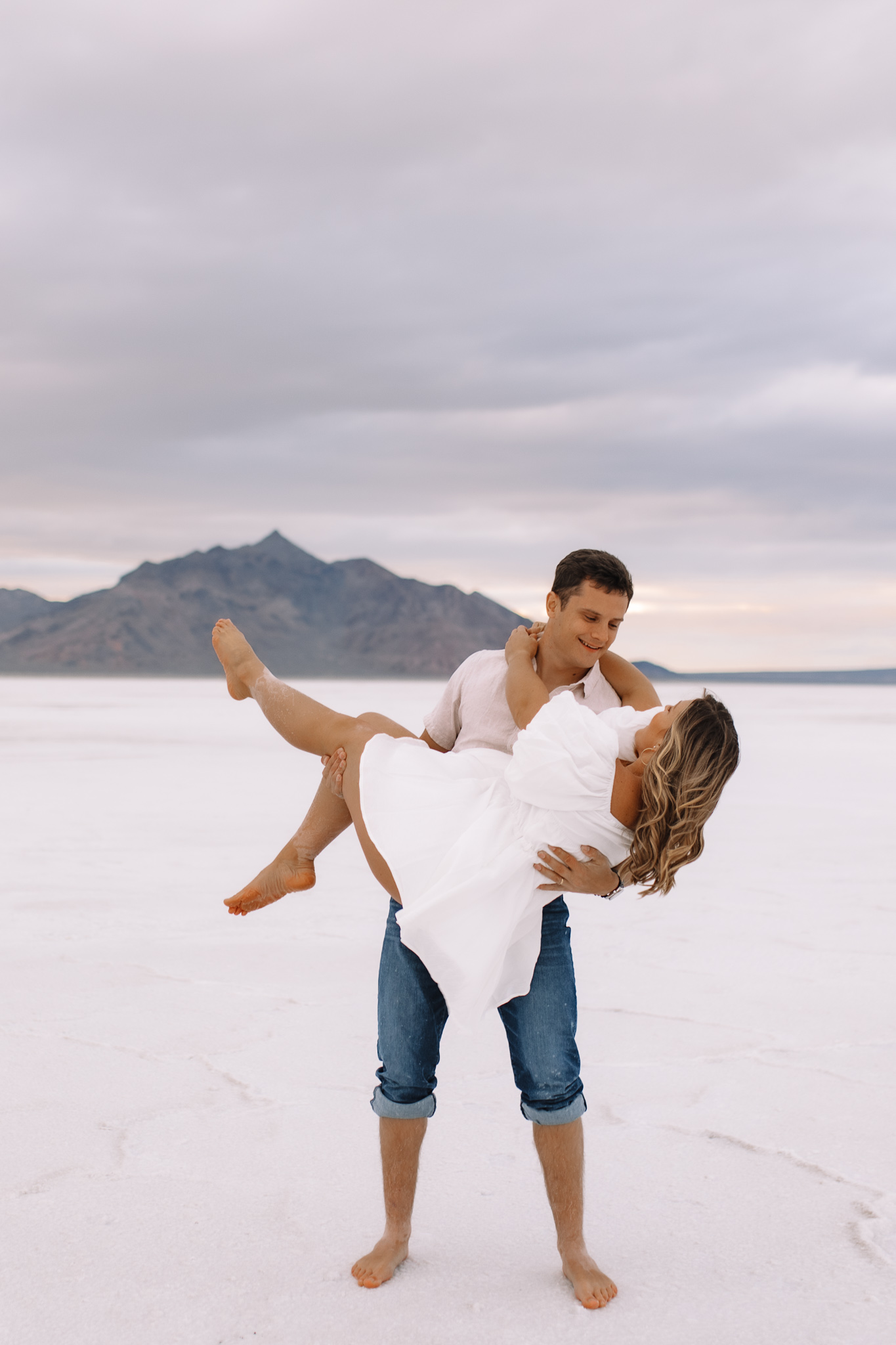 Groom picking up his bride like a baby on the white salt flats in Utah