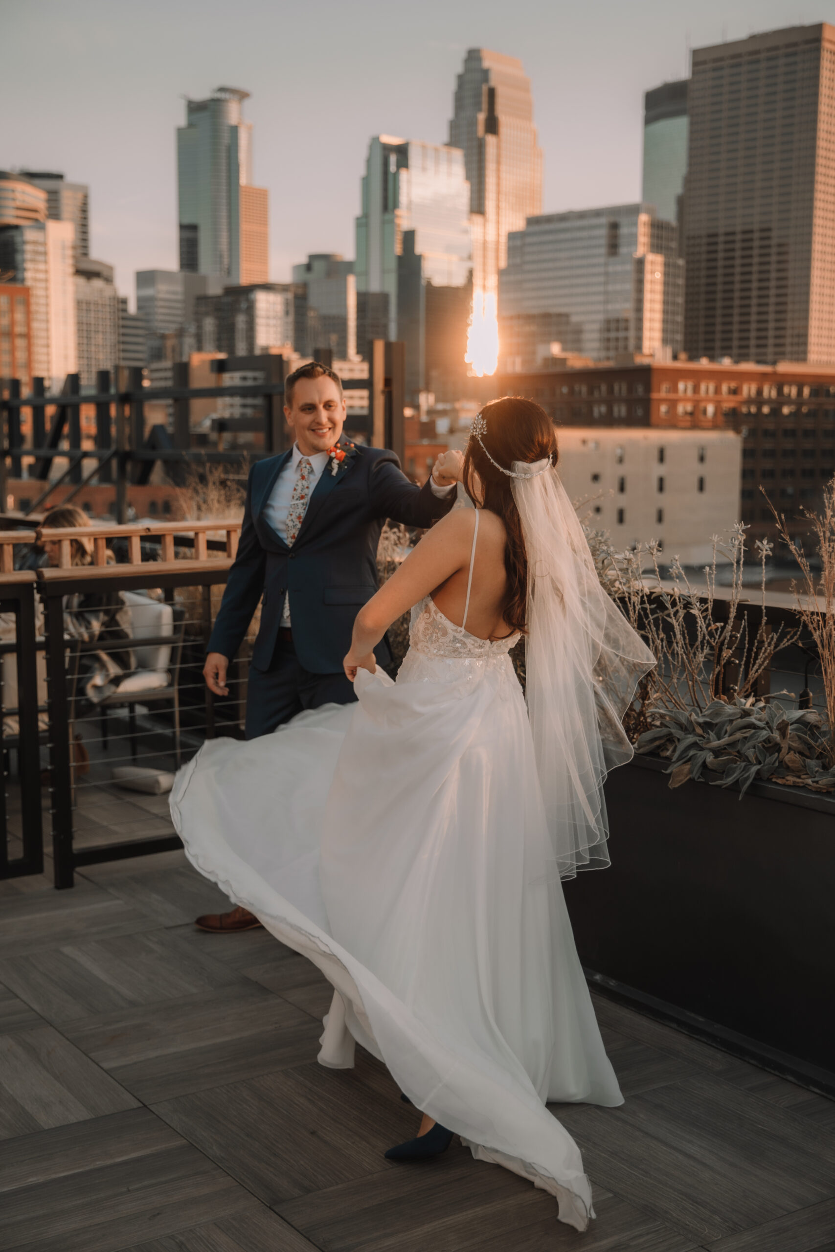 Bride and Groom dancing on top of a view deck overlooking the city of Minneapolis. The sun is reflecting off of the skyscrapers.