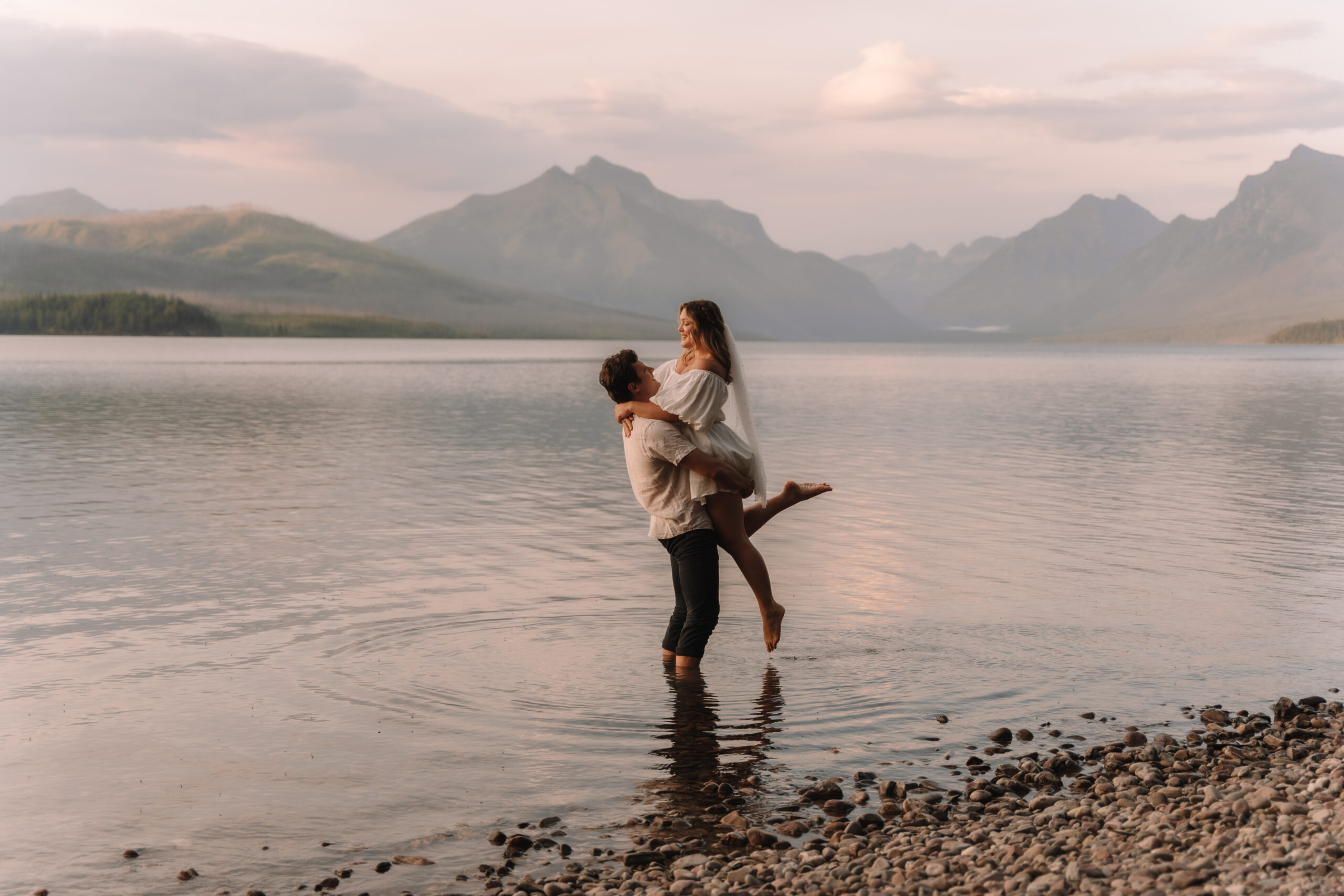 Groom picking up his bride in the water at Lake MacDonald in Glacier National Park