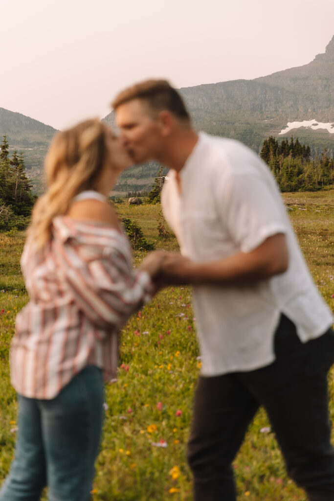 Newly engaged couple kissing on top of Logan's Pass in Glacier National Park