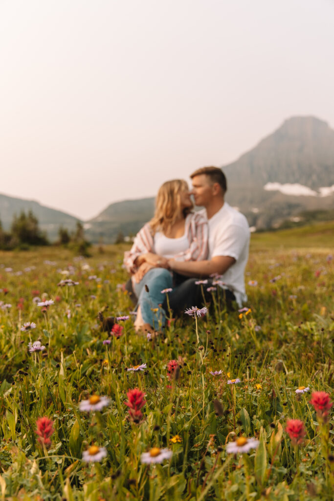 Newly engaged couple kissing on top of Logan's Pass in Glacier National Park