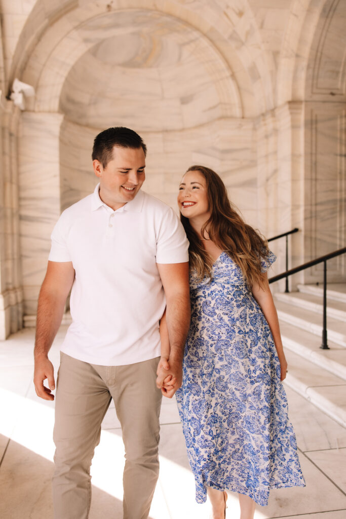 Engagement couple walking hand and hand smiling at each other during their engagement photos at the Minnesota State Capitol - One of the best engagement photo locations in Minneapolis