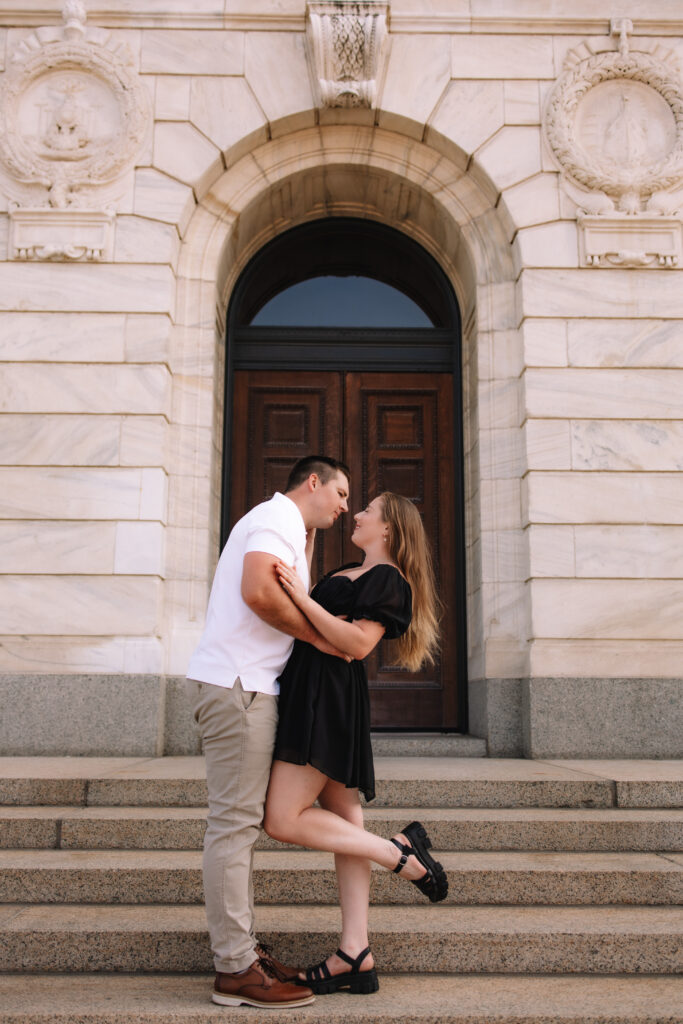 Guy gently dipping his girl backwards as he leans in for a romantic kiss during their engagement photos at the State Capitol of Minnesota