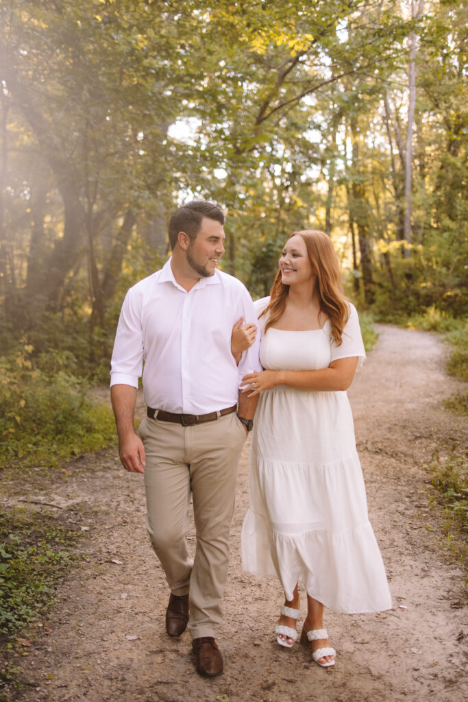 Engagement couple dressed in formal attire walking arm in hand down the pathway at Minihaha Falls in Minneapolis