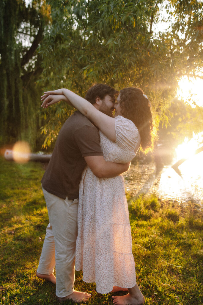 Engagement couple slow dancing next to Lake of the Isles in Minneapolis as the sun sets behind them