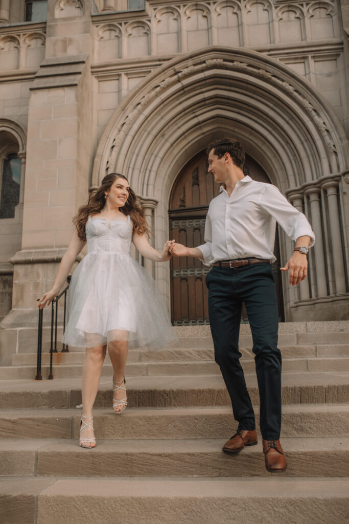 Engagement couple in formal attire running down the stairs of the American Institute of Art - One of the best engagement photo locations in Minneapolis