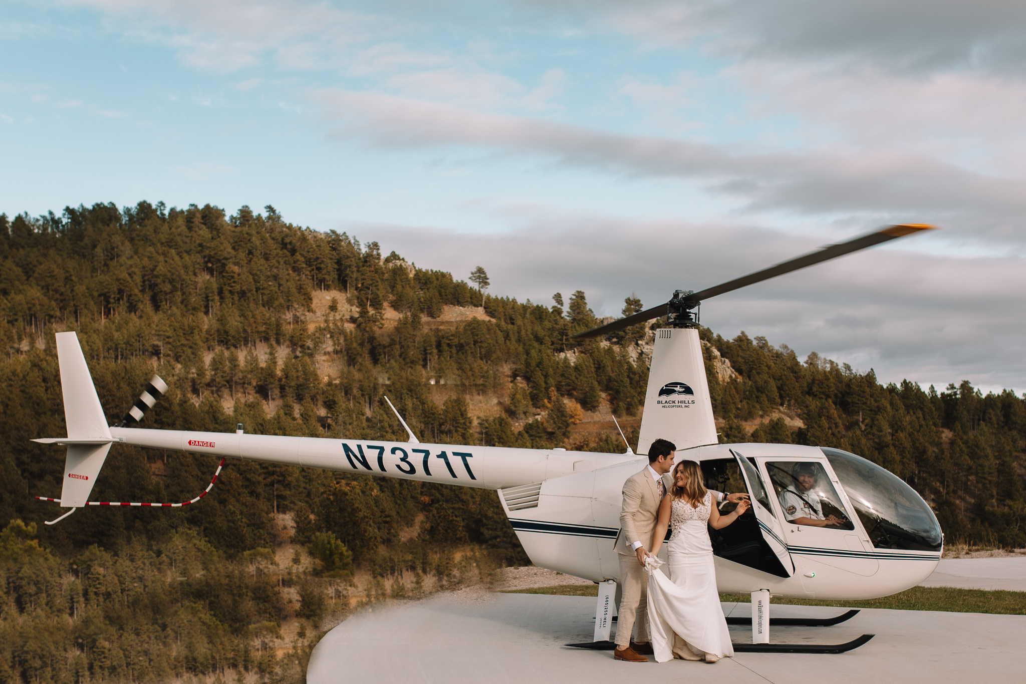 A bride and groom standing in front of the helicopter ready to climb in and fly over the black hill forrest in South Dakota