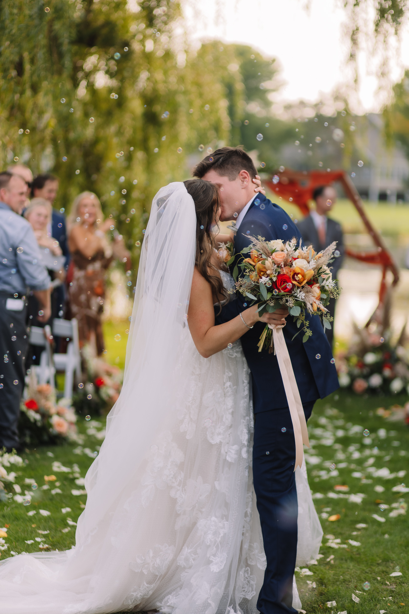 Bride and Groom First Kiss surrounded by bubbles between the willow trees at the Oak Glen Golf Club