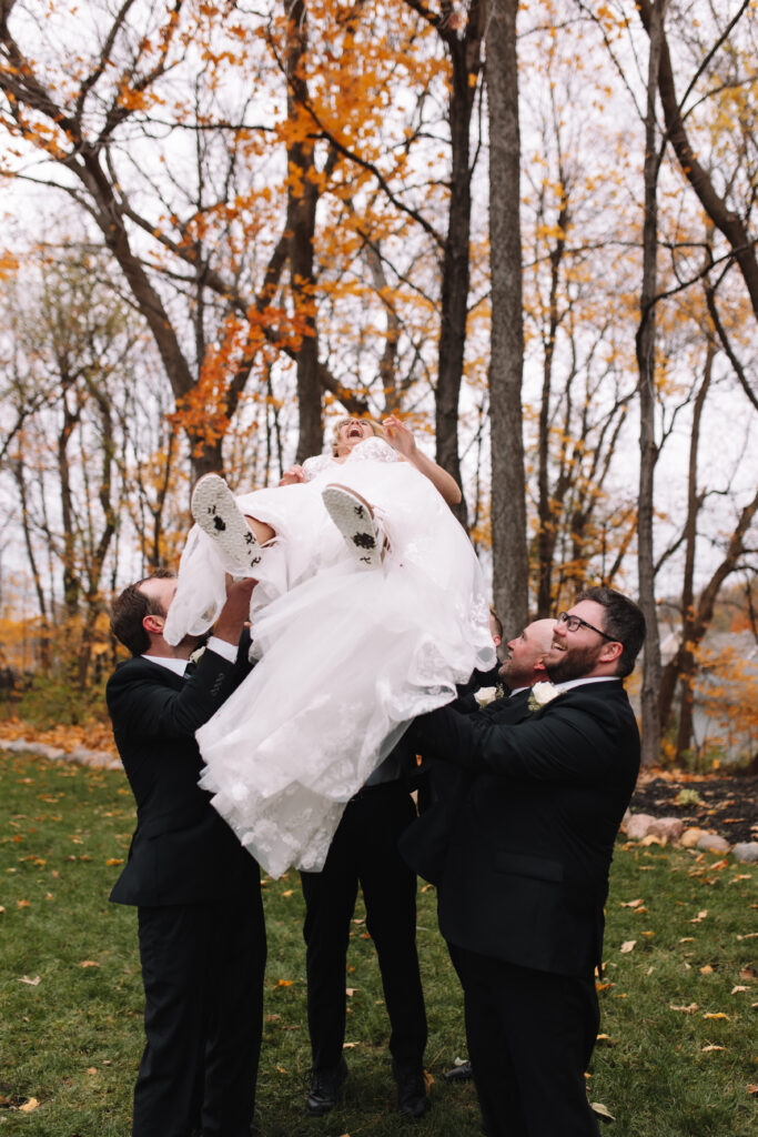 Bride getting thrown in the air by groomsmen on her wedding day in Minnesota