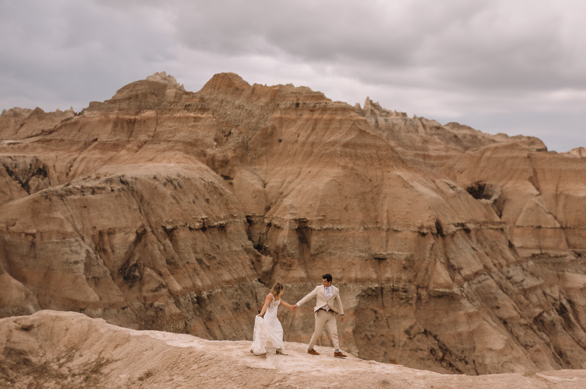 Elopement couple hiking in their wedding attire in the Badlands in South Dakota