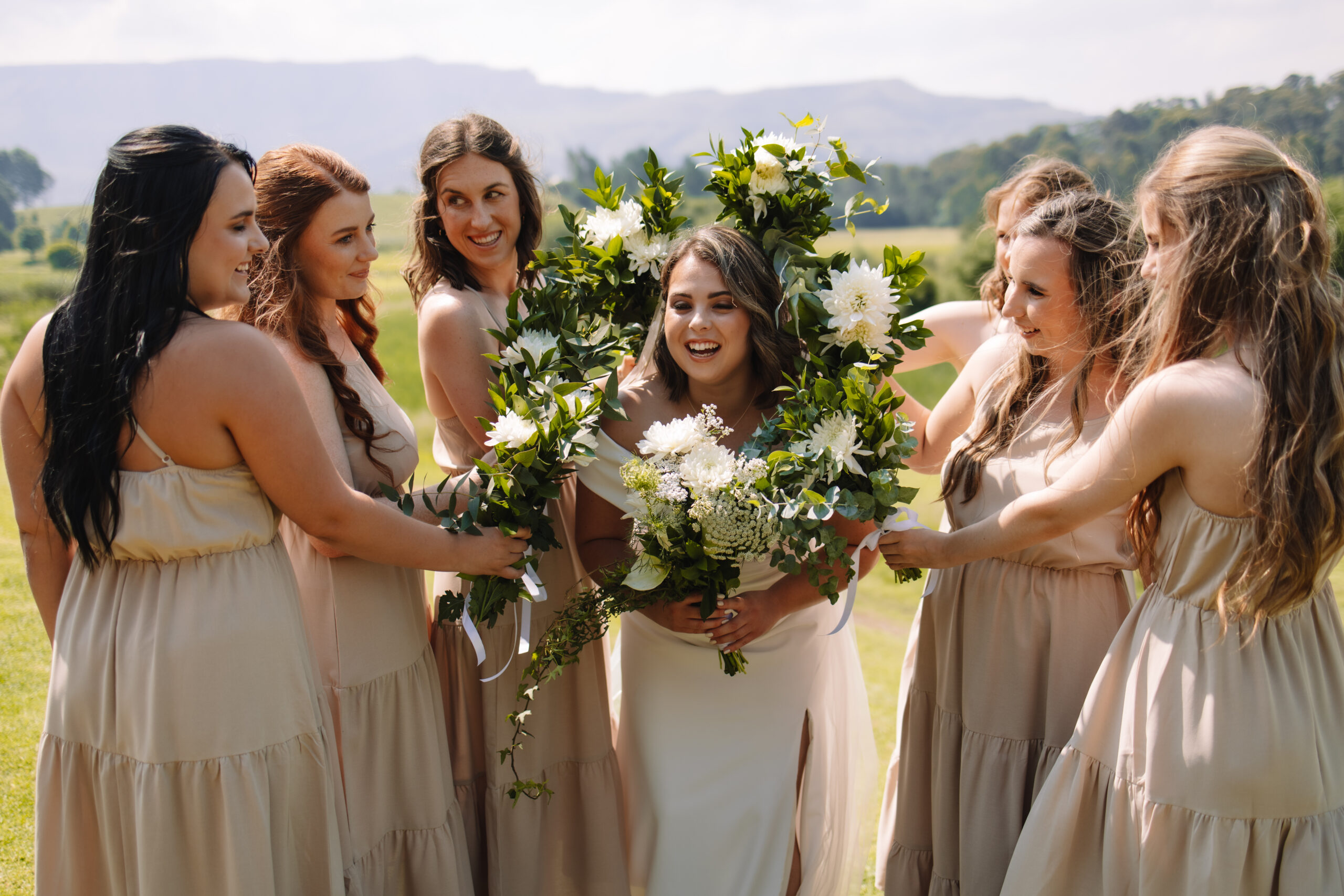 Bridesmaids surrounding bride's face with their bouquets 