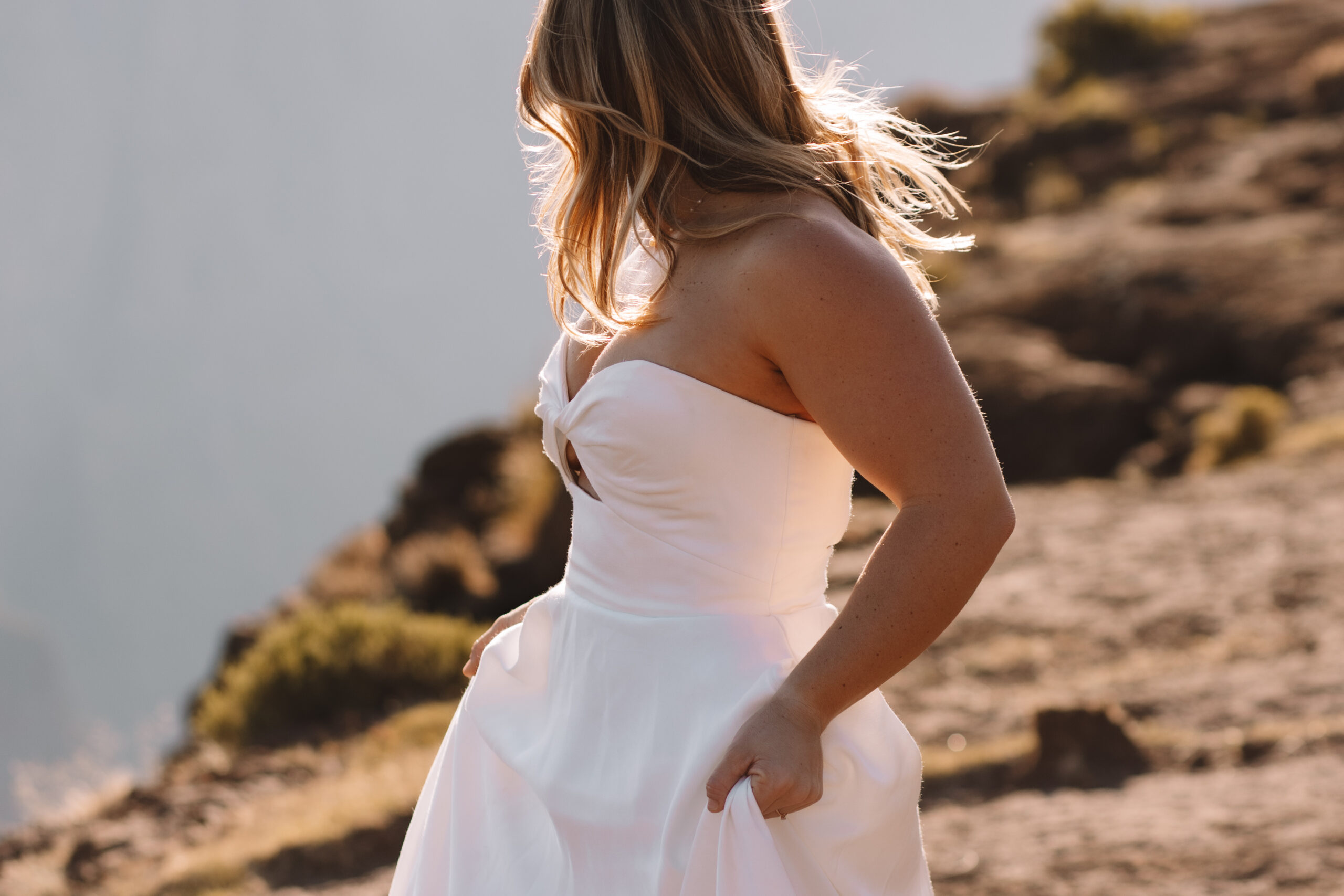 Healthy and happy bride in her plain white wedding dress on a mountain
