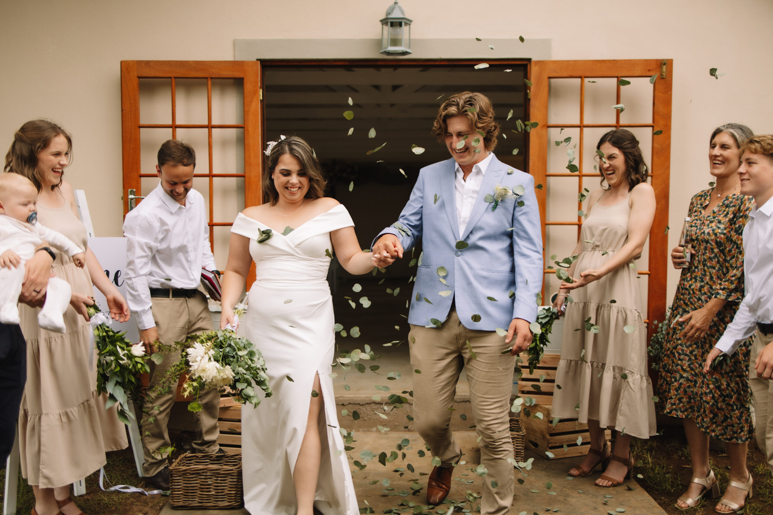 Wedding couple walking out of the church as guests throw eucalyptus confetti at them