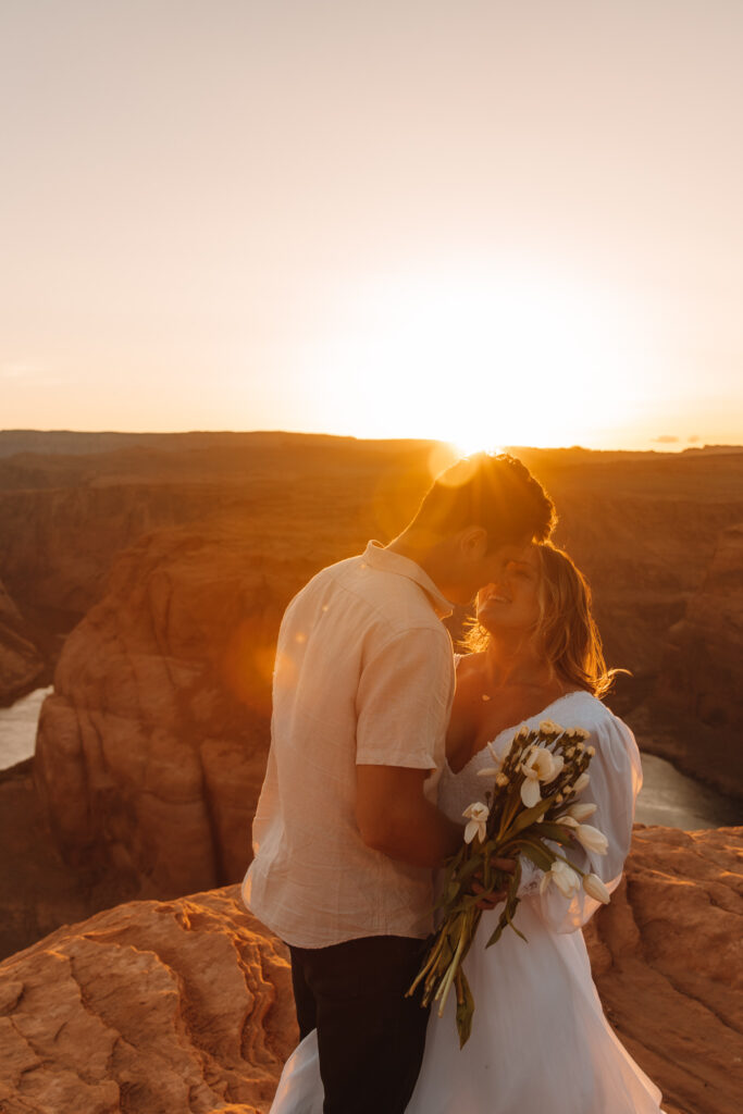 Bride and Groom embracing each other as the sun sets behind the cliff
