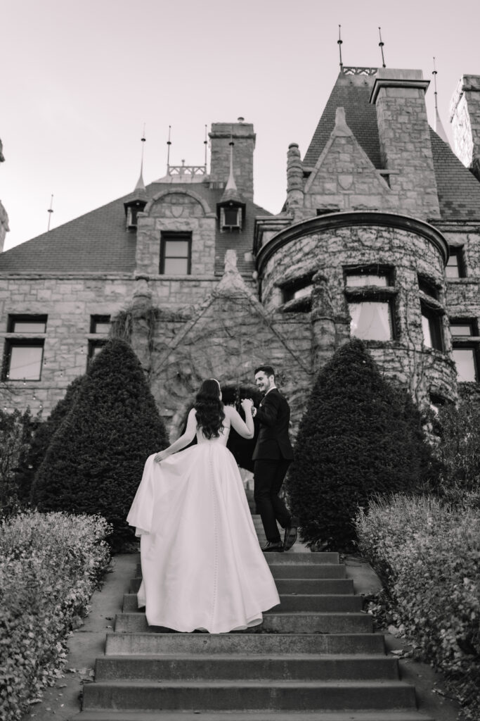 A groom leading his bride up the stairs in front of a big Mansion in Minnesota