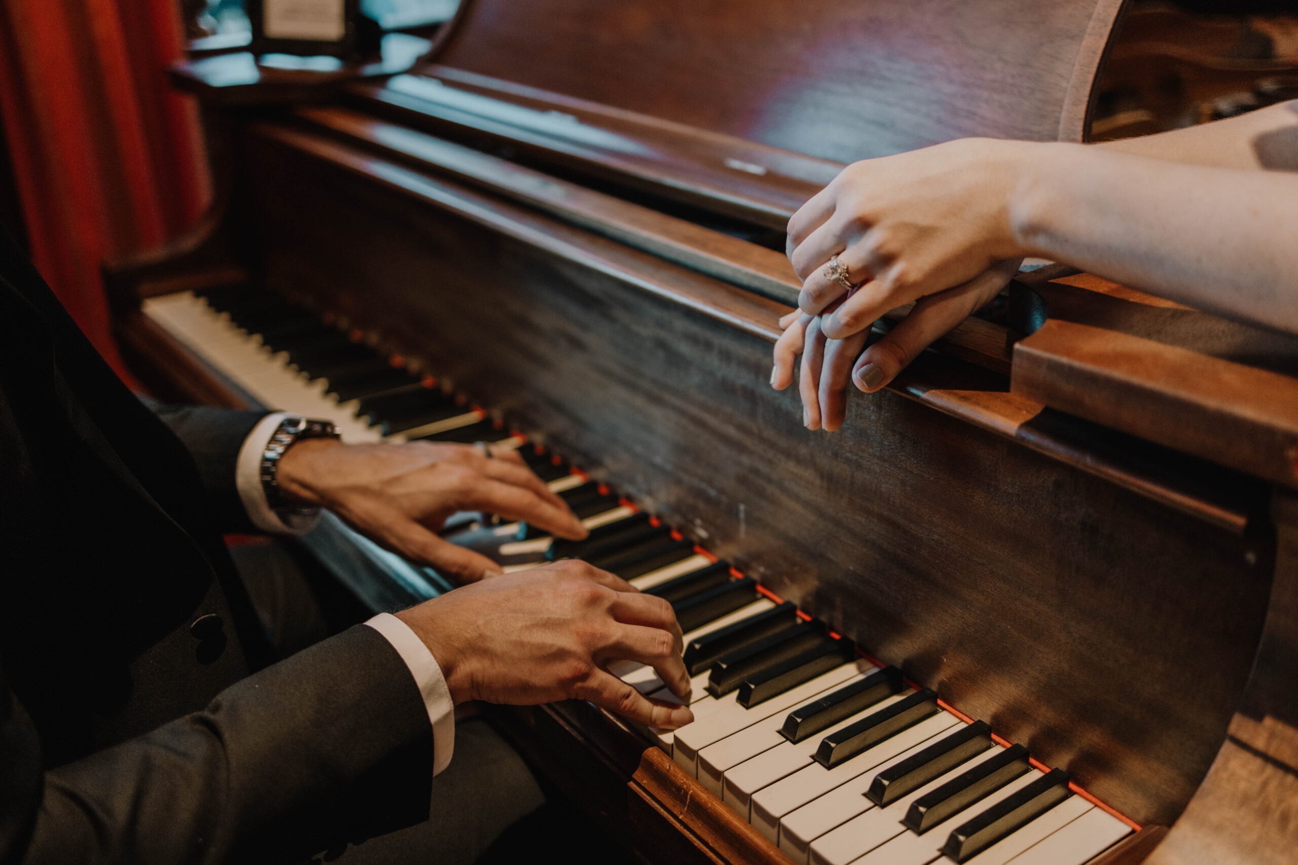 A close up photo of a Groom's hands playing the piano for his bride in a mansion in Minnesota