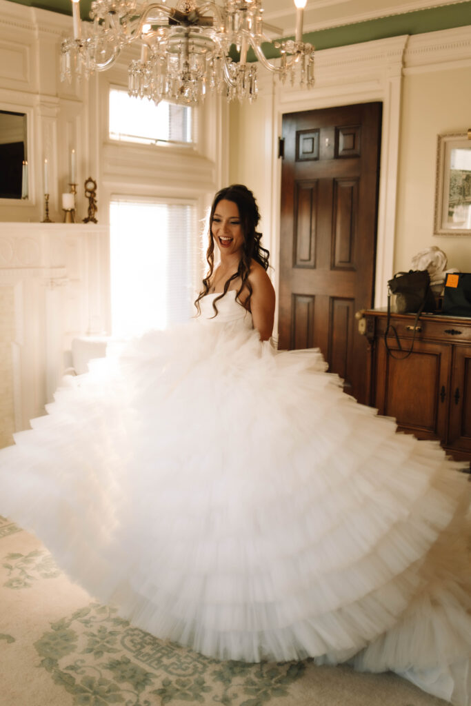 A bride dancing and swaying around in her voluptuous wedding dress in the bridal suite of the van dusen mansion in Minneapolis