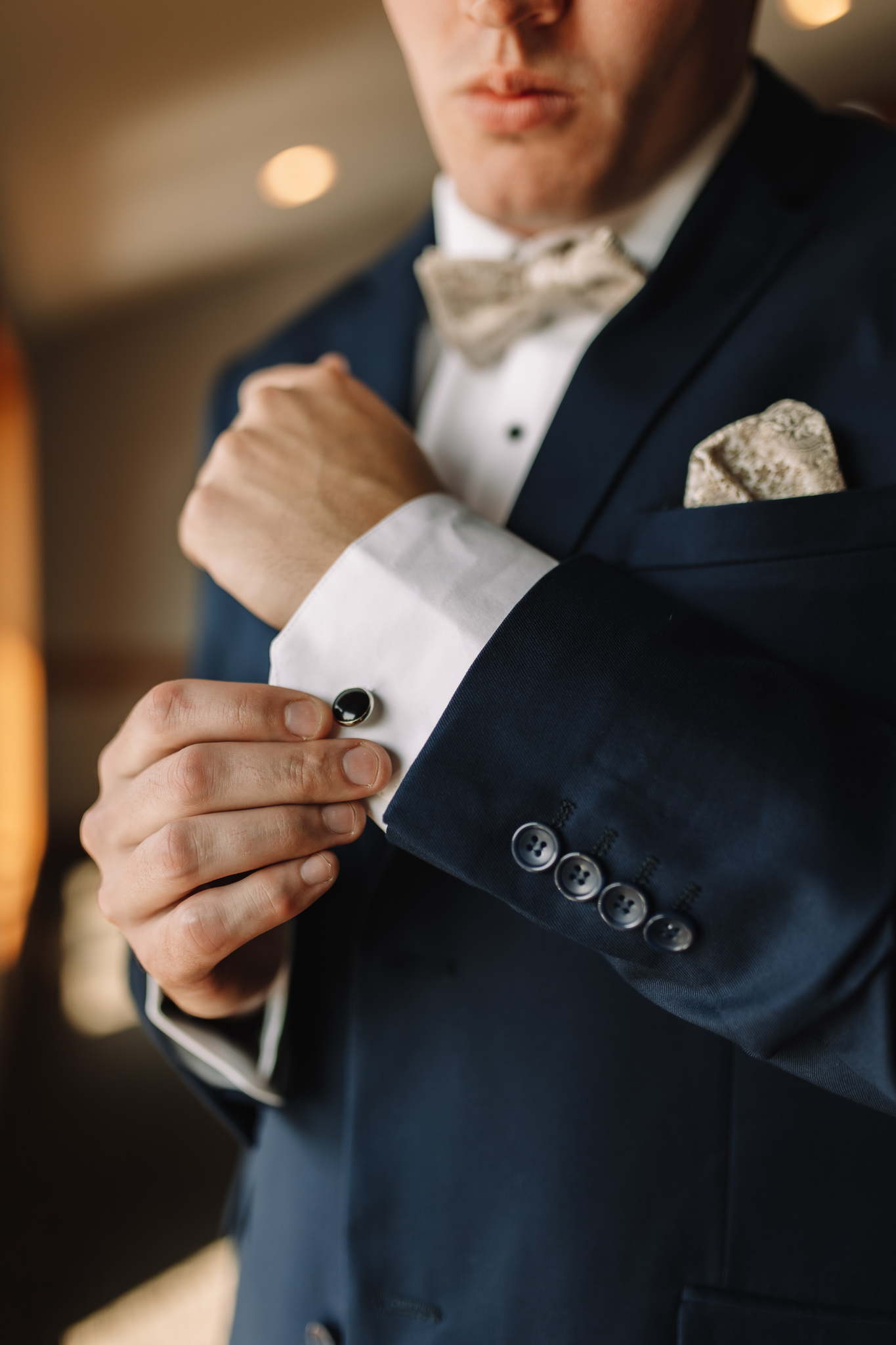 Groom with navy blue suit adjusting his cuffs on his white long sleeve shirt