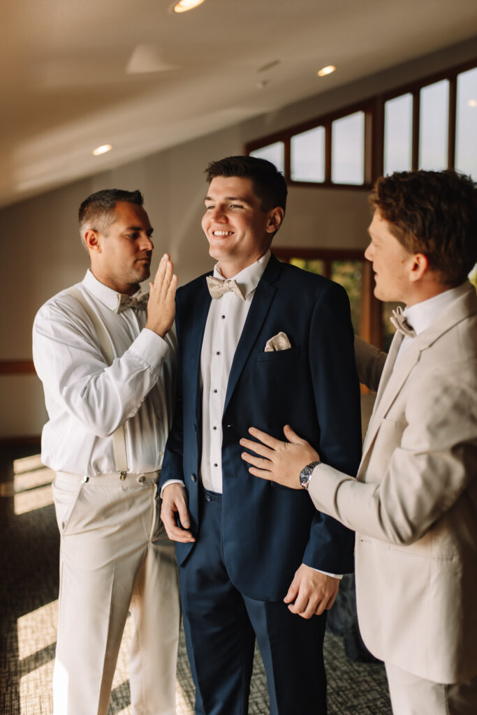 Wedding shot of groom with his best man and dad giving him encouraging taps on his back and shoulder in Minneapolis, MN
