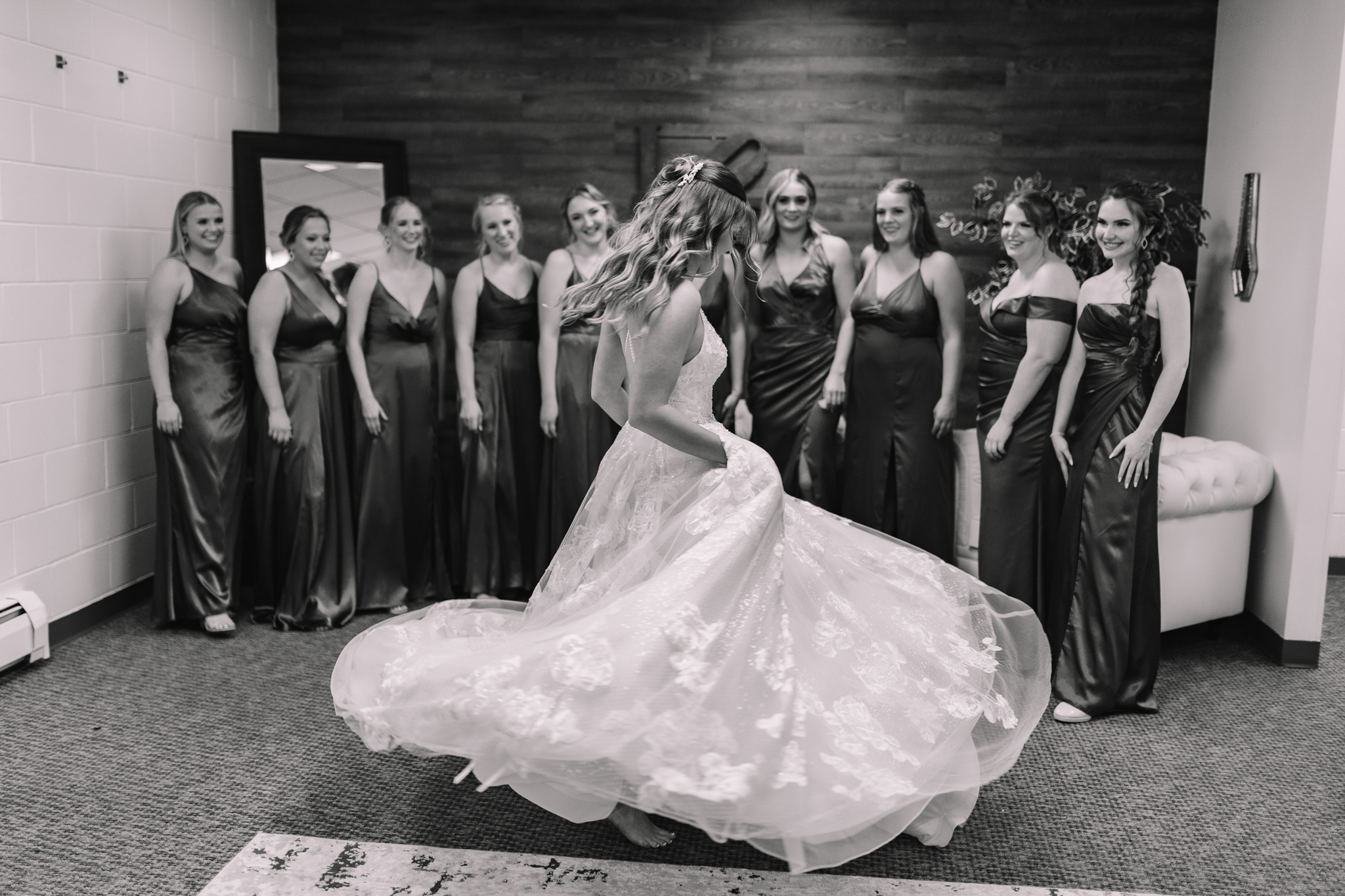 Bride twirling around showing off her wedding dress to her bridesmaids who are standing behind her admiring how beautiful she looks