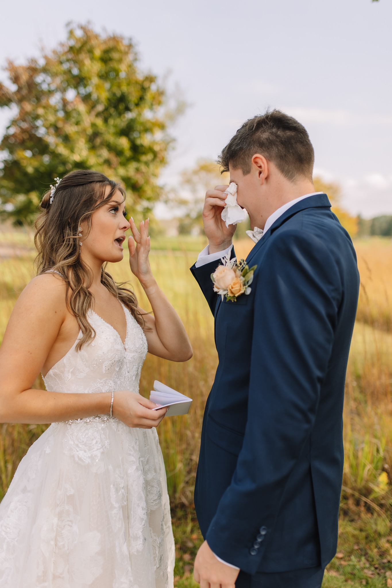 Emotional bride and groom exchanging private vows in a field with trees in Minnesota