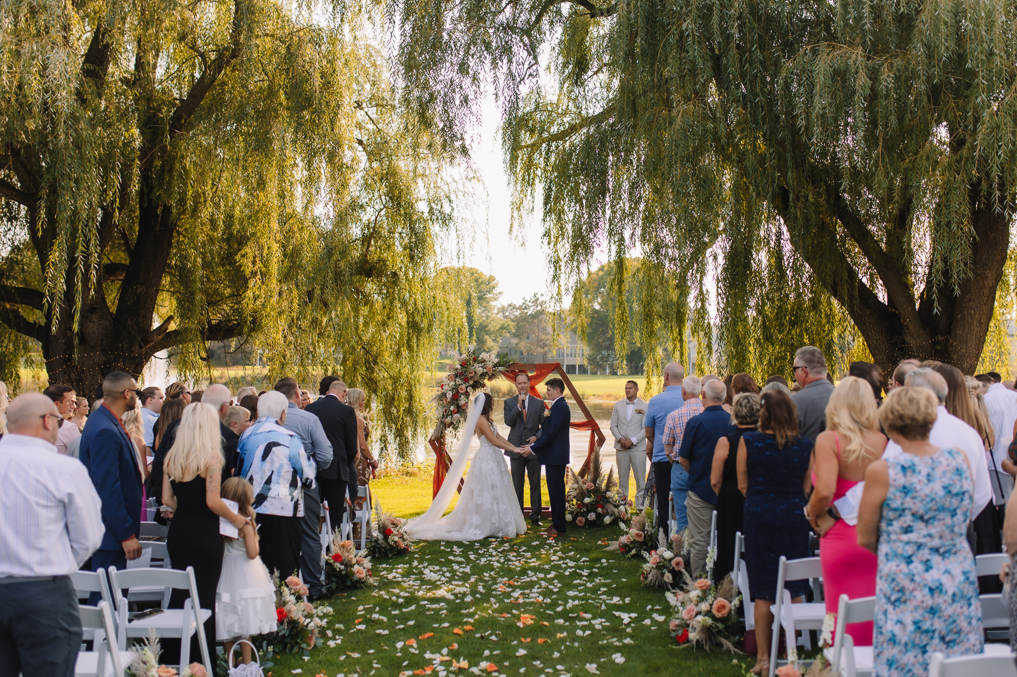 Beautiful outdoor summer wedding ceremony in Stillwater, Minnesota between two willow trees with a lake in the background
