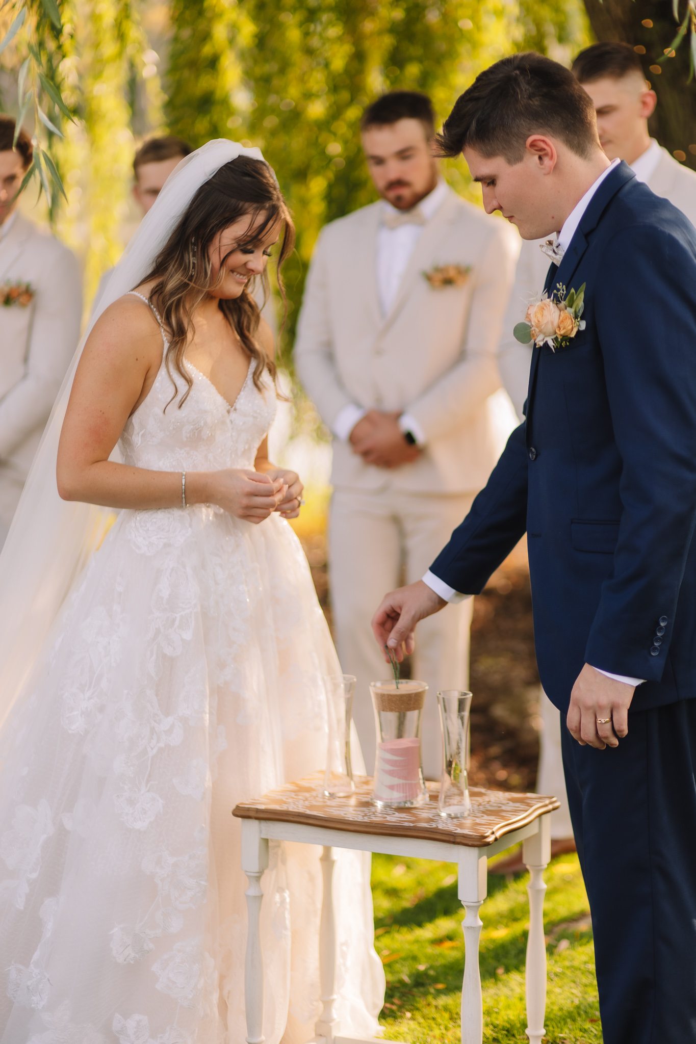 A bride and groom pouring colorful sand into a glass vase for their unity ceremony