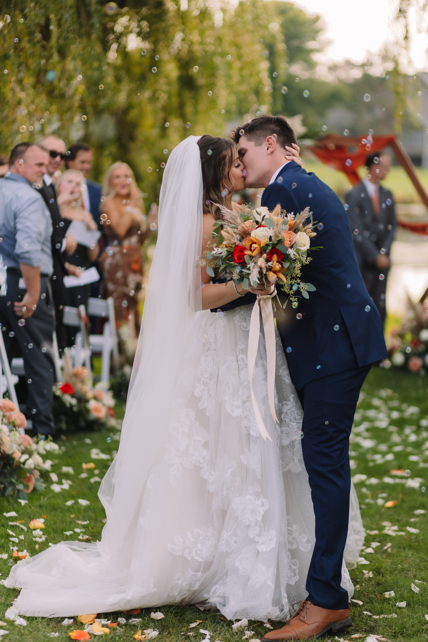 Bride and Groom kissing down the aisle as guests blow bubbles towards them