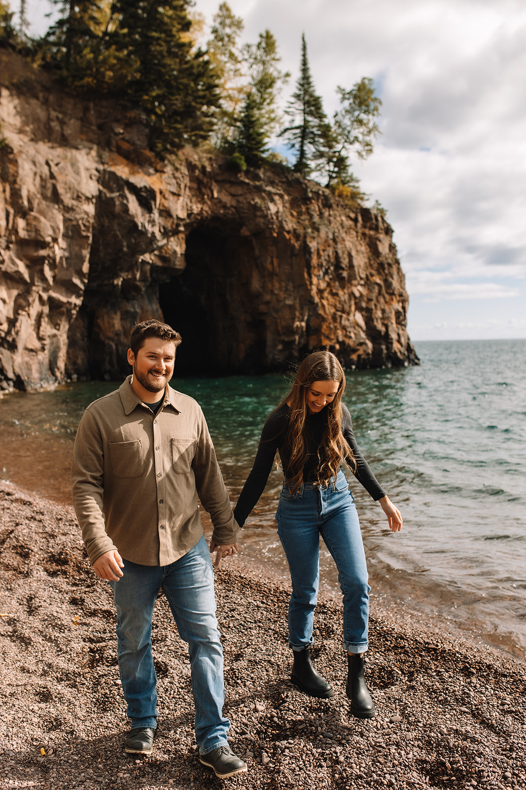 Engagement couple walking along a pebbled beach in Crystal Bay Minnesota