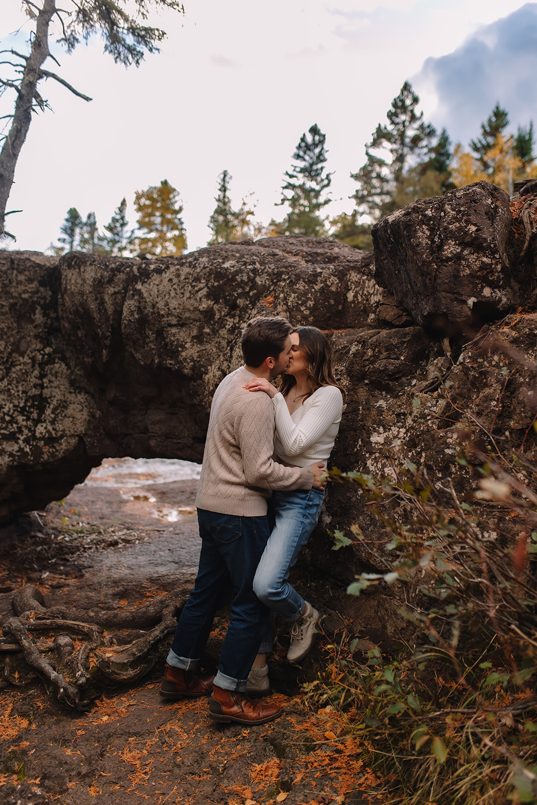 An engagement couple kissing each other tenderly at Gooseberry falls state park in Minnesota