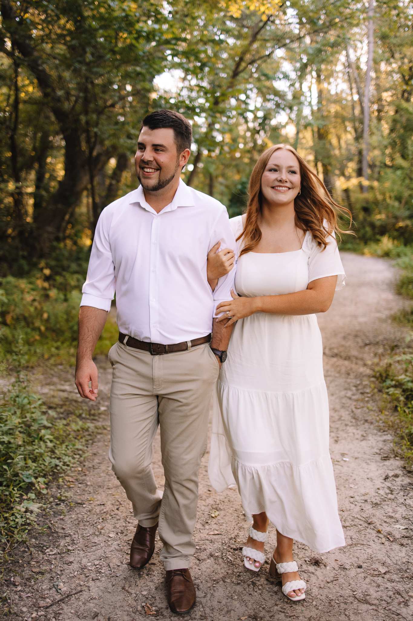 Engaged couple dressed in co-ordinating colors, walking hand in hand on a path in Minihaha Falls- perfect inspiration to help you decide what to wear for your engagement photos in Minnesota