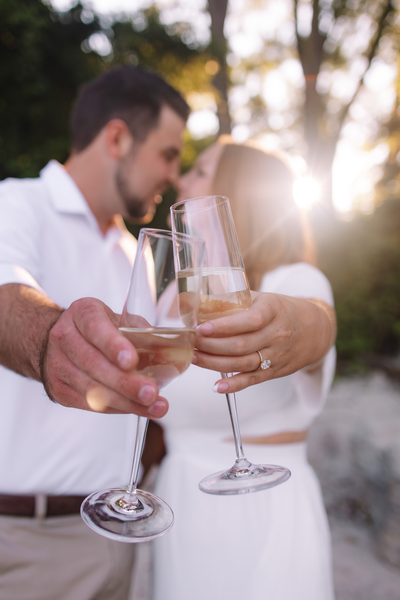 Engagement couple clinking their champagne glasses as they cheers and kiss to celebrate their engagement