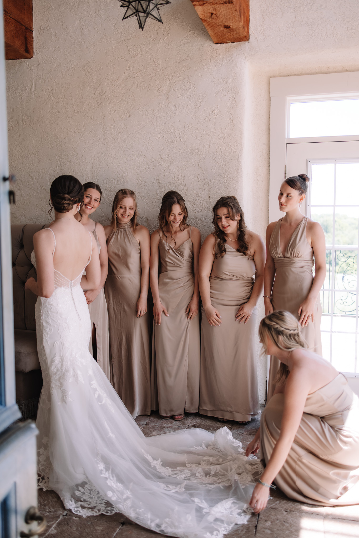 Bride and bridesmaids helping bride with wedding dress 