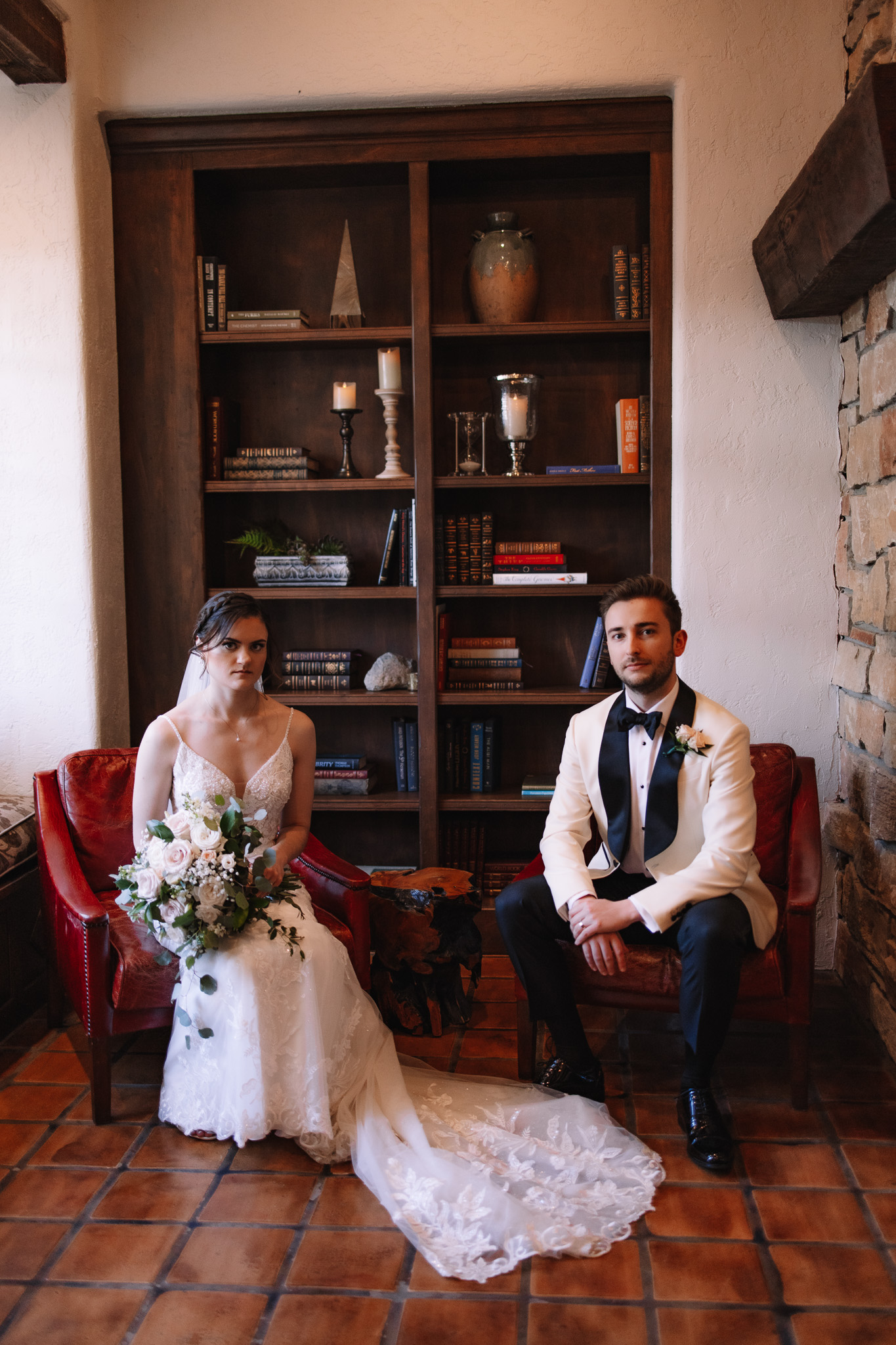 Bride and groom sitting inside Edward Anne Estate near a bookcase