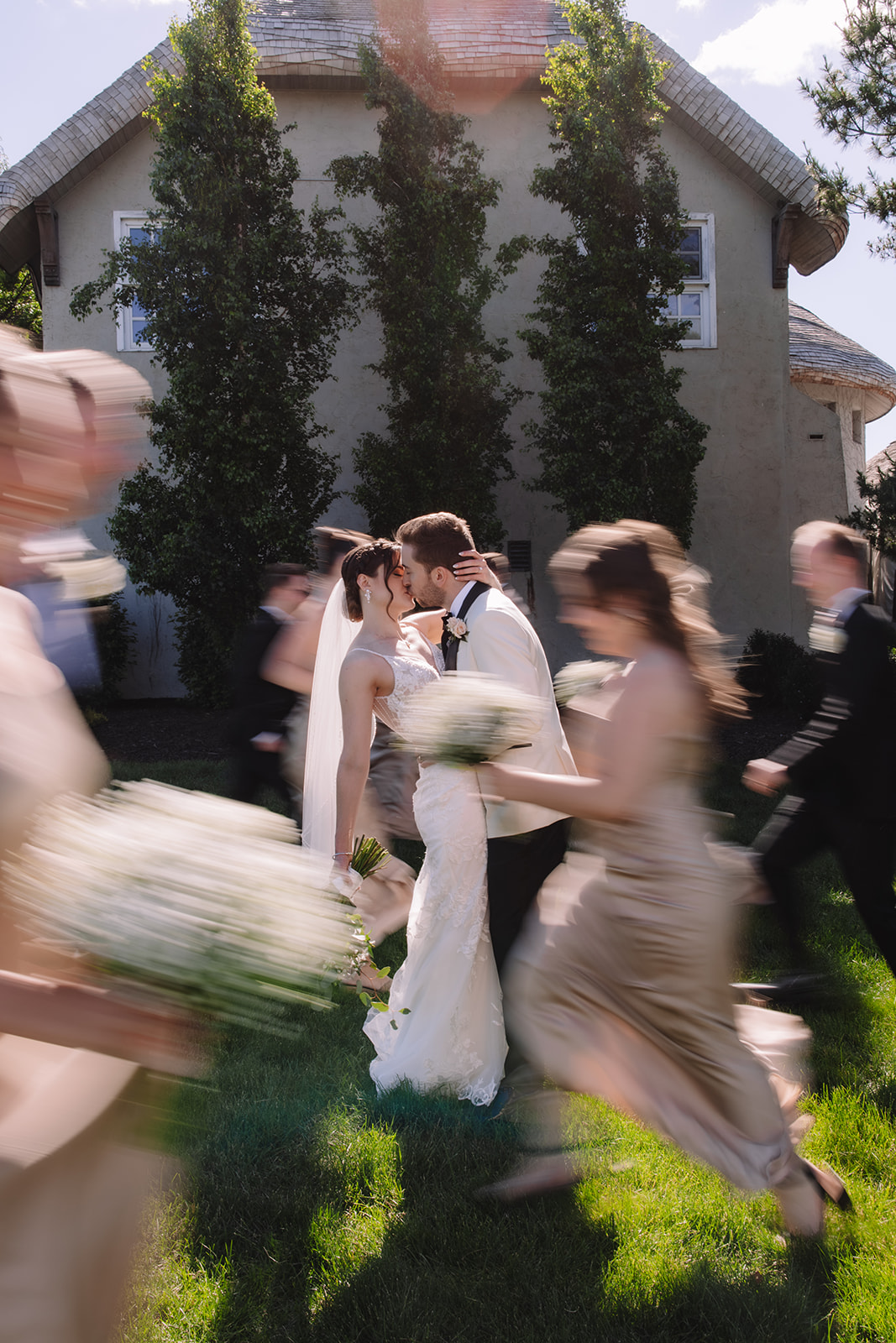 Bride and groom kissing while bridal party runs around them