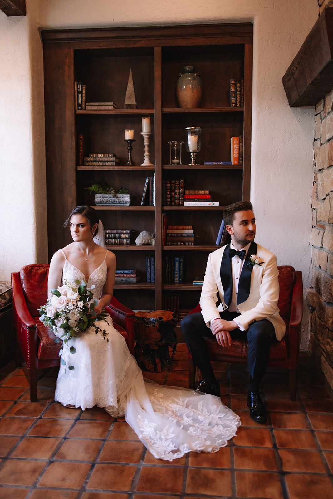 Bride and groom sitting inside Edward Anne Estate near a bookcase