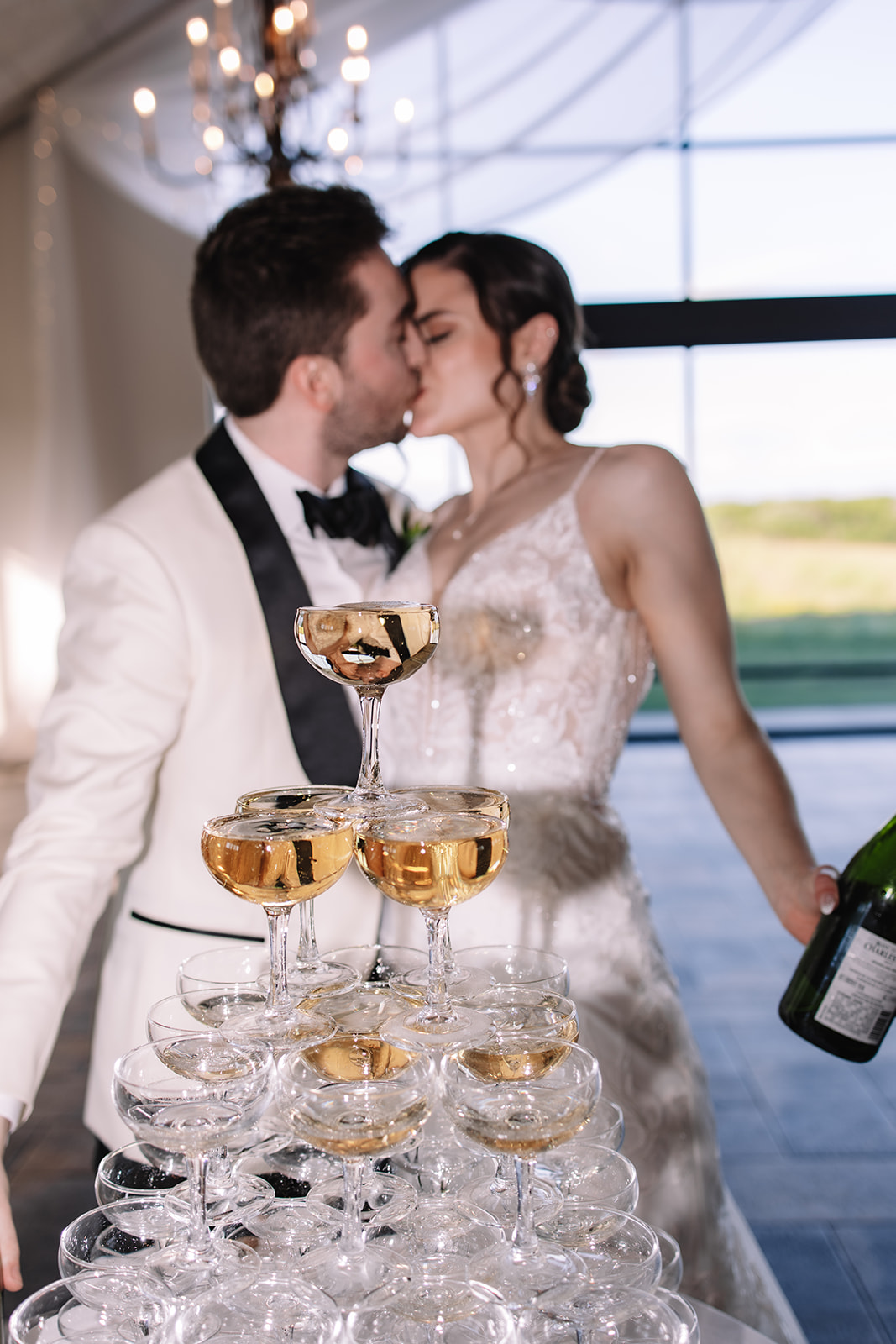 Bride and groom kissing in front of champagne tower