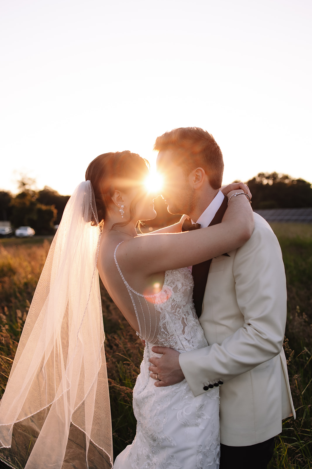 Bride and groom holding one another gazing into eachothers eyes during sunset 