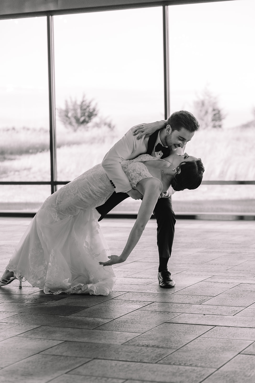 Black and white photo of groom dipping bride during their first dance 