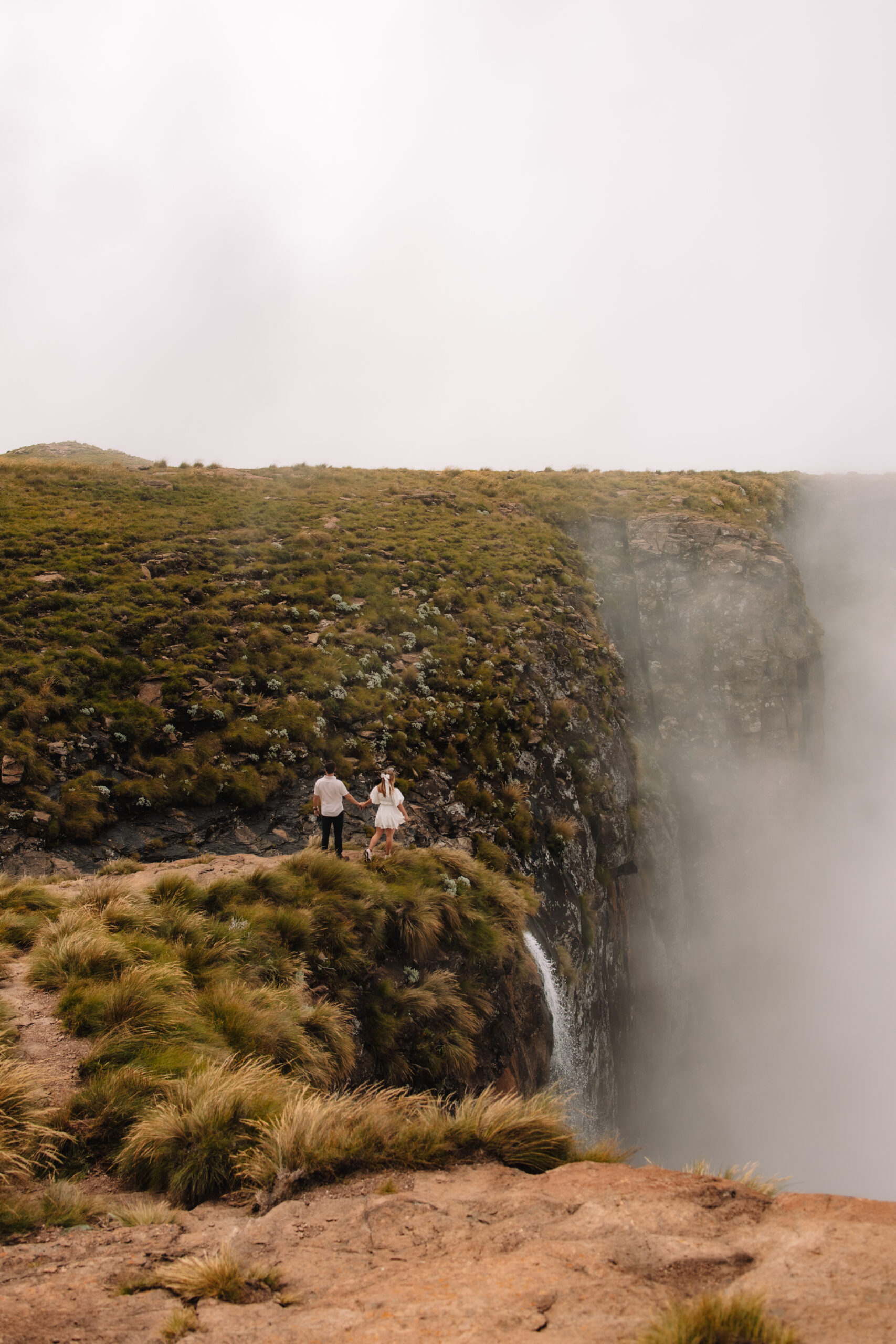 An elopement couple walking on a cliff towards the Tugela Falls in South Africa - One of the Top elopement spots in South Africa