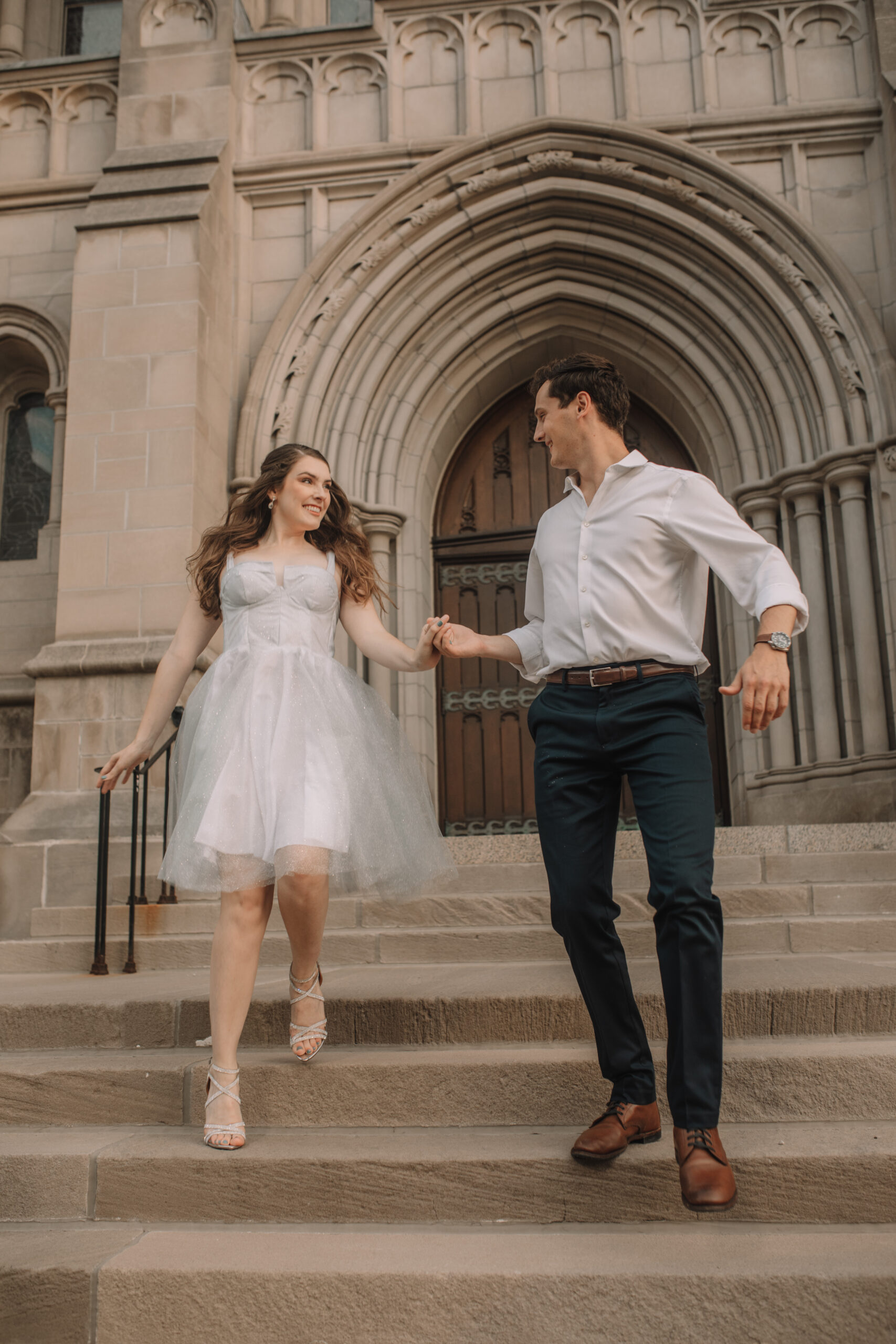 Newly engaged couple walking down stairs in front of the Minnesota State Capitol for their engagement photos