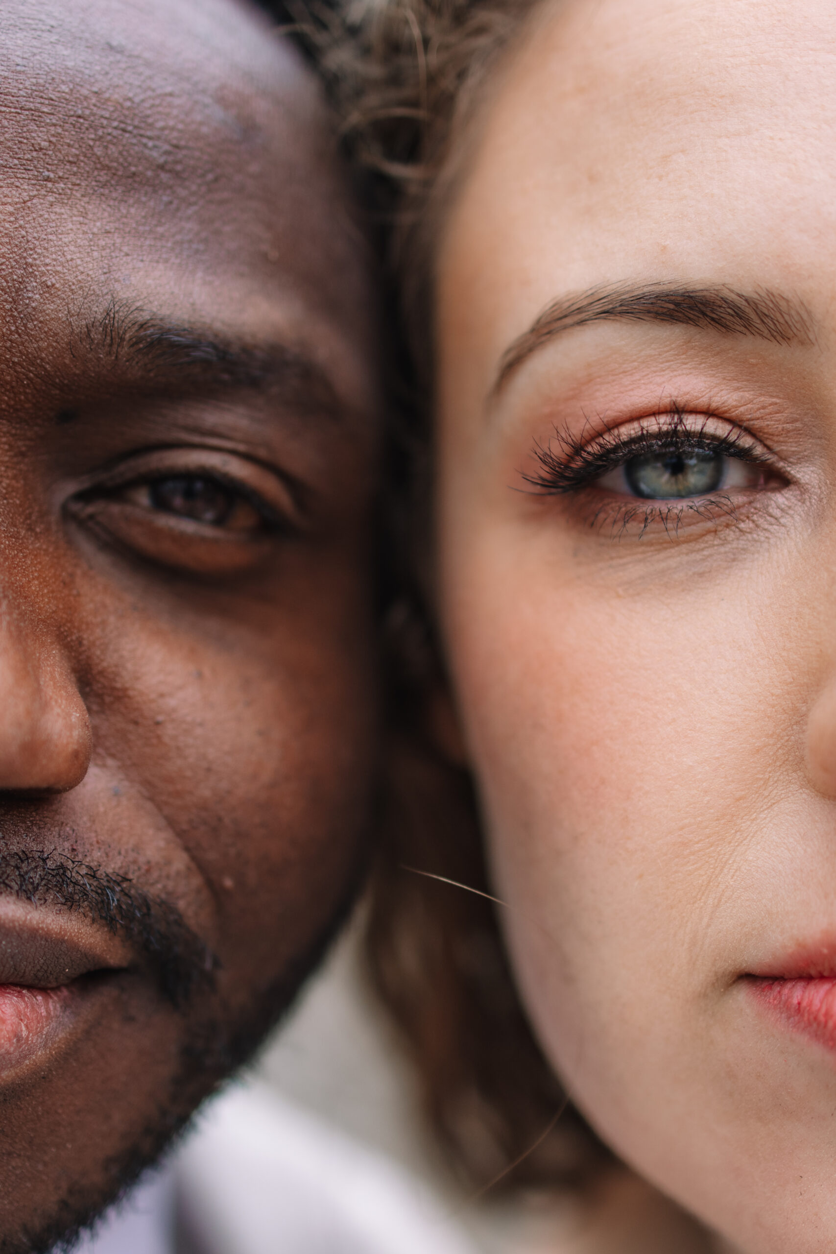 Close-up of the faces of two people, focusing on the left side of the man's face and the right side of the woman's face. Both are looking straight ahead.