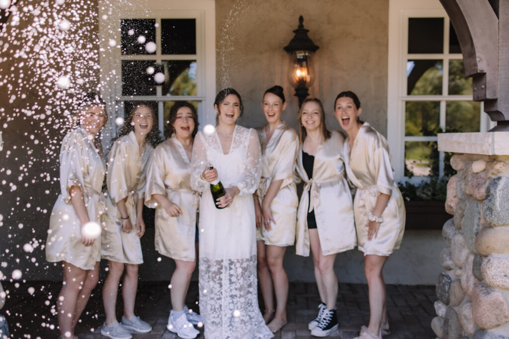 Bride and bridesmaids doing a champagne pop at Edward Anne Estate