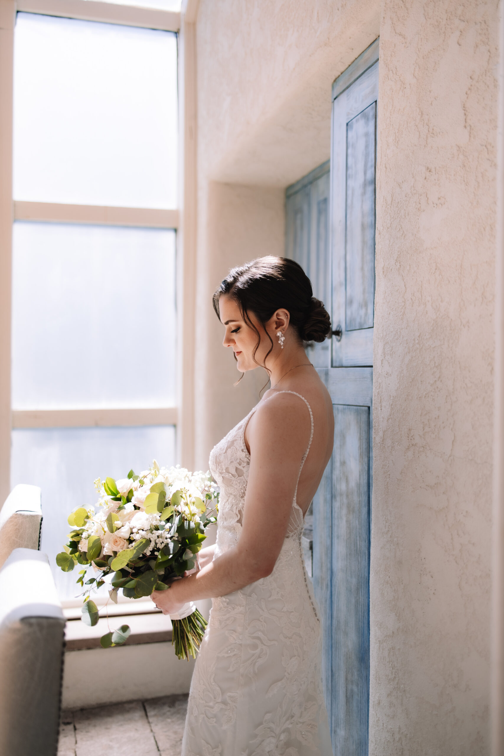 Bridal portrait of bride in a low back white wedding dress holding a white wedding bouquet