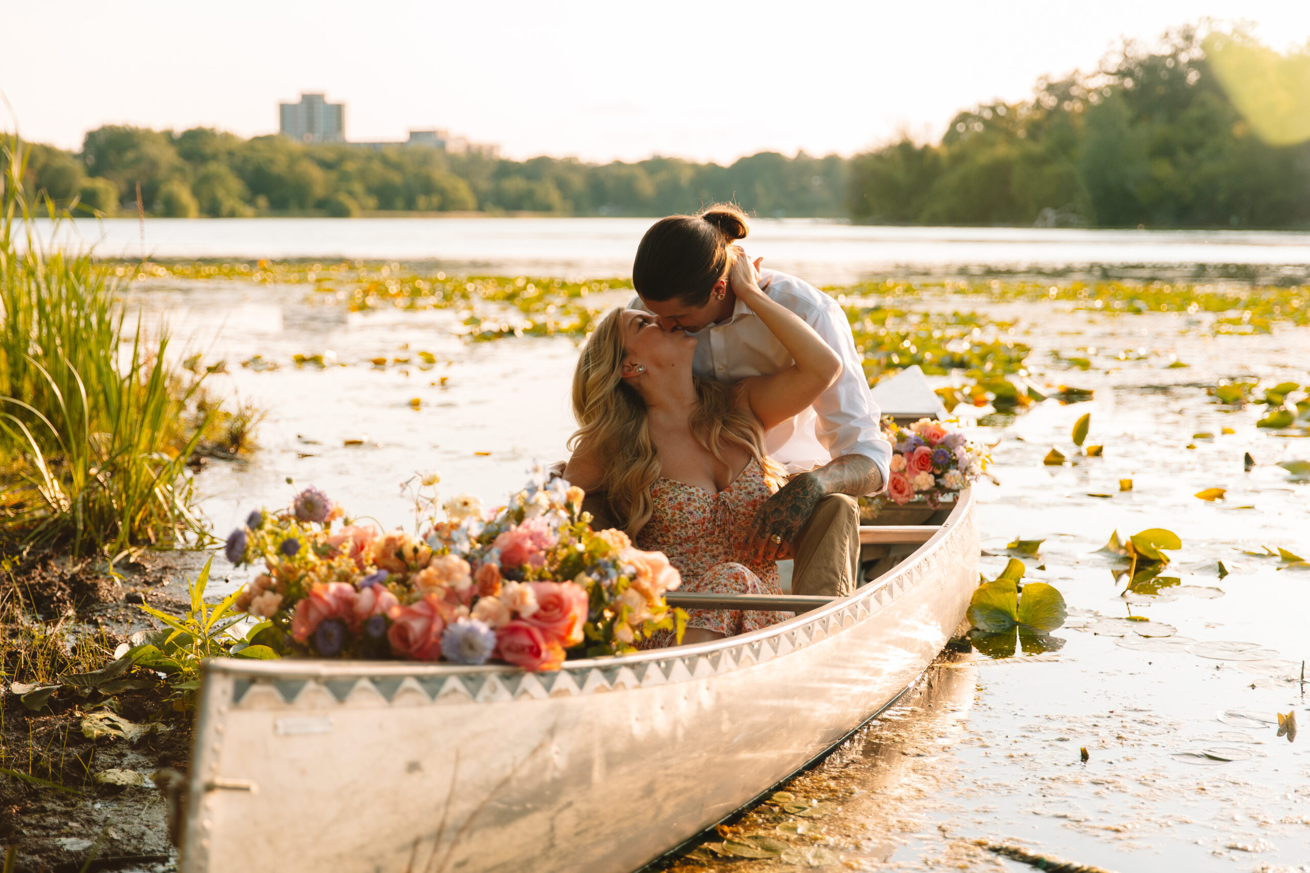 Newly engaged couple kissing in a canoe full of flowers
