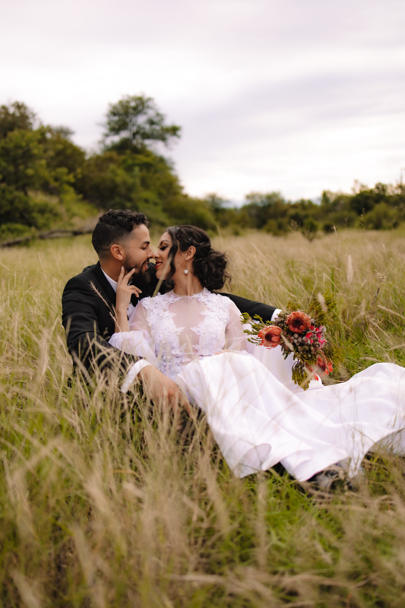 A South Africa elopement couple sitting between the grass in one of the top elopement spots in South Africa